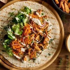 Pyszny kebab na tortilli z kurczakiem, sałatą, marchewką i cebulą, polany kremowym sosem do kebaba.