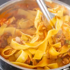 Gorący, parujący makaron pappardelle z sosem pomidorowym i warzywami, gotowy na szybki obiad z makaronem.