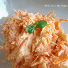 Pyszna surówka z marchewki z chrzanem, doprawiona i udekorowana listkiem bazylii. Idealna na każdą okazję.