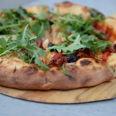 Pyszna pizza z rukolą i oliwkami, idealna na podstawie z przepisu na ciasto do pizzy.