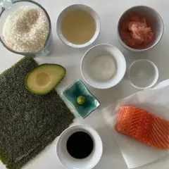 Świeży łosoś, ryż, awokado, nori i sos sojowy – oto składniki do sushi, gotowe do przygotowania pysznego posiłku.