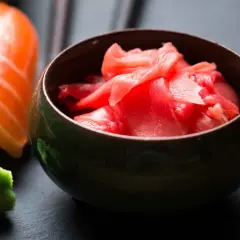 Miseczka z różowym, marynowanym imbirem obok sushi i wasabi. Idealny dodatek do japońskich smaków.