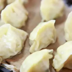Parowane pierożki dim sum, delikatnie ułożone na brązowym papierze, kuszą swoim wyglądem.