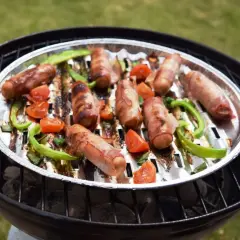 Pyszna kiełbasa z grilla, zawinięta w boczek, pieczona z papryką i pomidorkami na rozgrzanym ruszcie.