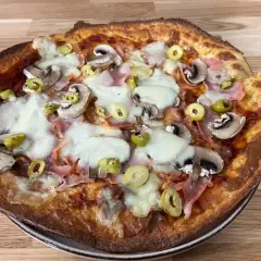 Pyszna pizza z twarogu z pieczarkami, szynką i oliwkami, zapieczona na złoto.