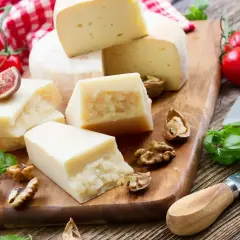 Różne rodzaje sera, orzechy, figi i pomidorki koktajlowe na desce. Idealne składniki, by wybrać, jaki ser do carbonary będzie najlepszy.