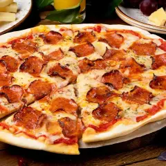 Pyszna pizza pepperoni z ciągnącym serem, obok serowe dodatki do pizzy, winogrona i kieliszek czerwonego wina.