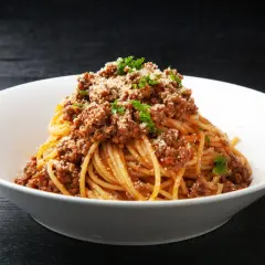 Pyszne spaghetti z mięsem mielonym, posypane parmezanem i natką pietruszki. Idealny prosty przepis na obiad.