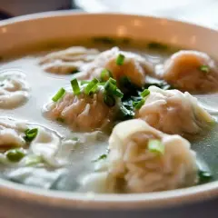 A miseczce paruje aromatyczna zupa won ton, ozdobiona szczypiorkiem.