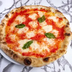 Pyszne ciasto na pizzę neapolitańską z pomidorami, mozzarellą i bazylią, idealne na letni wieczór.