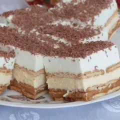 Szybkie ciasto bez pieczenia z budyniem i herbatnikami, udekorowane wiórkami czekolady. Idealne na deser.
