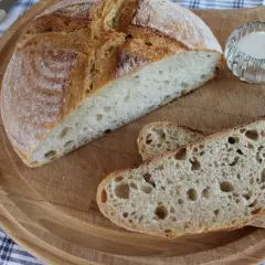 Chleb żytni na zakwasie, pokrojony na desce, z solniczką i nożem w tle. Idealny na śniadanie.