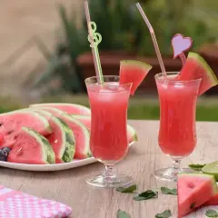 Orzeźwiająca lemoniada arbuzowa z plasterkami arbuza, cytryny i limonki na drewnianym stole.