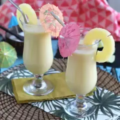 Dwa orzeźwiające koktajle pina colada z plasterkiem ananasa i parasolkami. Idealne na letnie popołudnie.