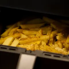 Ziemniaki pokrojone w frytki, przyprawione i gotowe do pieczenia w airfryerze. Pyszne dania z airfryer to szybki sposób na chrupiące frytki.