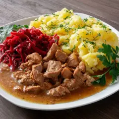 Tradycyjny gulasz wieprzowy z ziemniakami i buraczkami, ozdobiony natką pietruszki i koperkiem. Pyszne danie obiadowe.