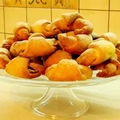 Stos rogalików drożdżowych, przygotowanych według przepisu babci, na szklanej paterze.