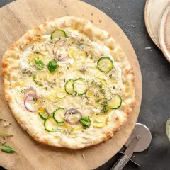 Pyszna pizza bianca z cukinią, cebulą i cytryną, podana na drewnianej desce.