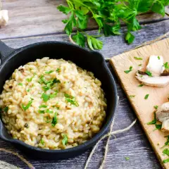Kremowe risotto z grzybami i natką pietruszki w czarnej patelni.