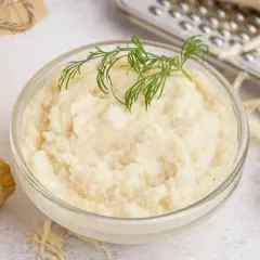 Domowy chrzan do słoików: świeży korzeń, tarta masa w misce i słoik z przetworem.