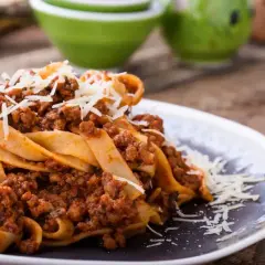 Pyszne tagliatelle z sosem bolognese, posypane parmezanem. Idealne danie, gdy zastanawiasz się, ile smażyć mięso mielone do spaghetti.