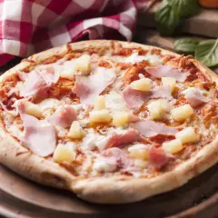 Apetyczna pizza z ananasem i szynką, polana ciągnącym się serem, na drewnianej desce.