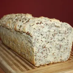Chleb z siemienia lnianego, z chrupiącą skórką i bogatym wnętrzem pełnym ziaren, na drewnianej desce.