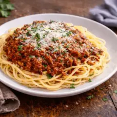 Pyszny sos do spaghetti przepis na talerzu, posypany parmezanem i natką pietruszki. Idealny na szybki obiad.