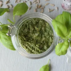 Domowe pesto z bazylii w słoiku, obok nasion słonecznika i czosnku. Idealne, by dowiedzieć się, jak zrobić pesto.