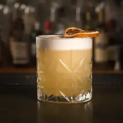 Klasyczny whisky sour przepis: orzeźwiający koktajl z pianką i plasterkiem suszonej pomarańczy.