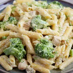Penne z kurczakiem i brokułami w kremowym sosie, posypane parmezanem. Pyszne danie obiadowe.