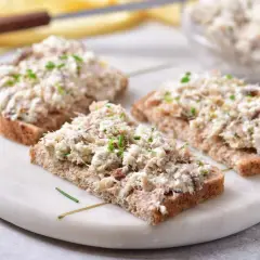 Trzy kromki ciemnego chleba z obfitym smarowidłem z makreli i twarogu, posypane szczypiorkiem. Idealna pasta na kanapki.