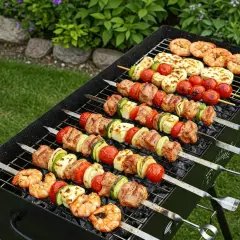 Grill pełen nietypowych dań z grilla: krewetki, ser halloumi, mięso i warzywa na szaszłykach.