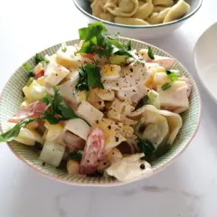 Pyszna sałatka z tortellini, jajka, kukurydzy i pomidorów, udekorowana natką pietruszki. Idealna na letnie dni, to najlepsza sałatka z tortellini.