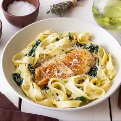Pyszny makaron z kurczakiem i szpinakiem, posypany parmezanem. Idealny na szybki obiad.
