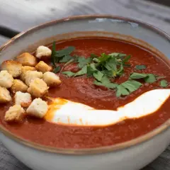 Aksamitny pomidorowy krem, przypominający smakiem butter masala, z grzankami, śmietaną i natką pietruszki.