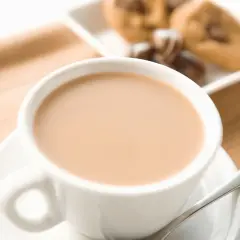Aromaticzne cafe au lait w białej filiżance, obok ciasteczka z kawałkami czekolady. Idealny poranek.