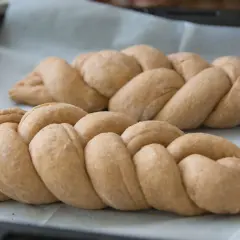 Dwie plecione chałki na papierze do pieczenia. Zastanawiasz się nad chałka kcal?