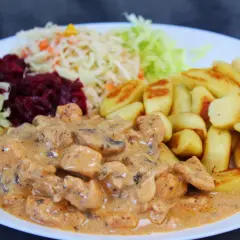 Pyszny gulasz z piersią z kurczaka w kremowym sosie, podany z ziemniaczanymi kluskami i surówkami.