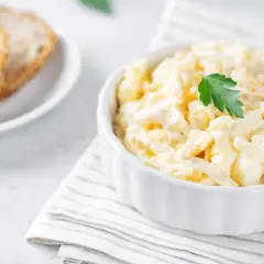 Kremowa, pyszna najlepsza sałatka z kalafiora, udekorowana natką pietruszki, obok kromek chleba.