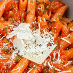 Penne w sosie pomidorowym z parmezanem i ziołami. Pyszne danie z makaronem, które zachwyca smakiem i aromatem.