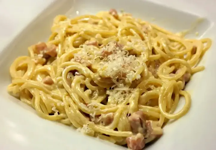 Pyszne spaghetti carbonara z kawałkami guanciale i parmezanem. Idealna śmietana do carbonary to sekret tego dania.