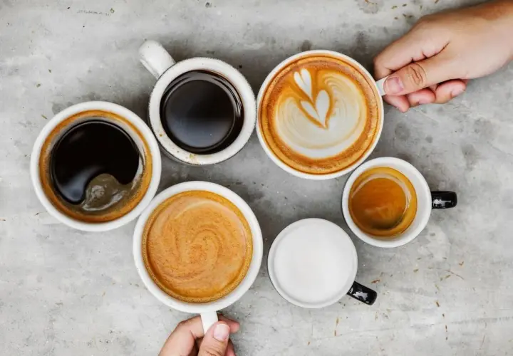Różne rodzaje kawy, od espresso po latte, ułożone na szarym blacie. Czy kawa wypłukuje magnez? To pytanie nurtuje wielu miłośników tego napoju.