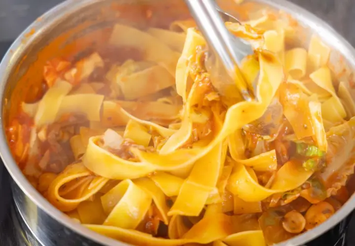 Gorący, parujący makaron pappardelle z sosem pomidorowym i warzywami, gotowy na szybki obiad z makaronem.