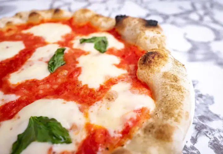 Pyszna pizza Margherita, klasyczny włoski przepis. Idealnie wypieczone ciasto, sos pomidorowy, mozzarella i świeża bazylia.
