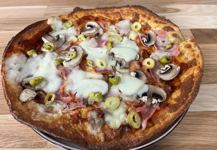 Pyszna pizza z twarogu z pieczarkami, szynką i oliwkami, zapieczona na złoto.