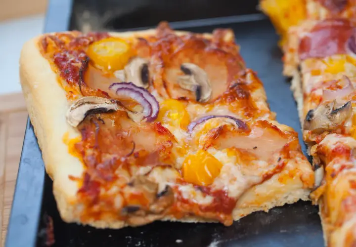 Domowa pizza na blachę, pachnąca świeżymi drożdżami, z pieczarkami, cebulą i pomidorkami. Idealna na rodzinny obiad.