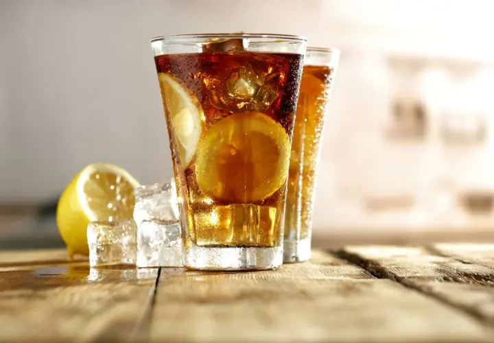 Orzeźwiający Long Island Ice Tea z cytryną i lodem na drewnianym blacie.