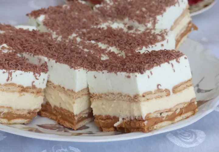 Szybkie ciasto bez pieczenia z budyniem i herbatnikami, udekorowane wiórkami czekolady. Idealne na deser.