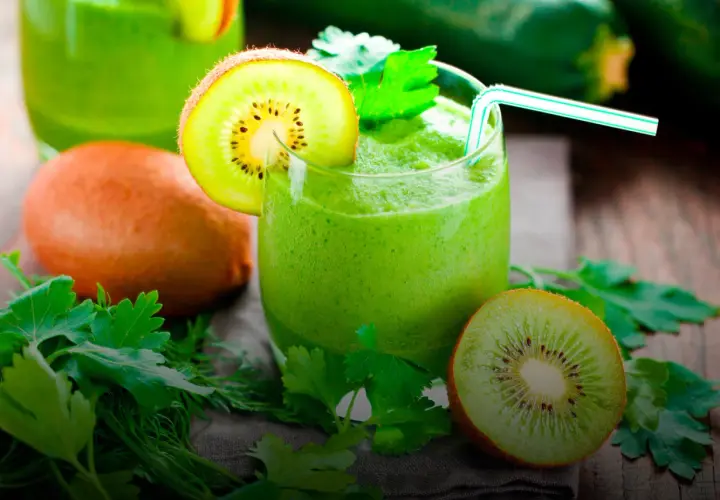 Zielony koktajl z kiwi i ziołami, udekorowany plasterkiem kiwi.